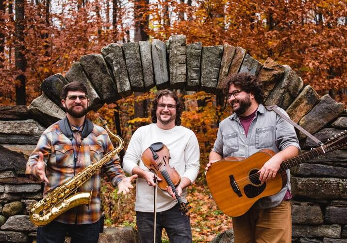 Three musicians under stone arch in autumn